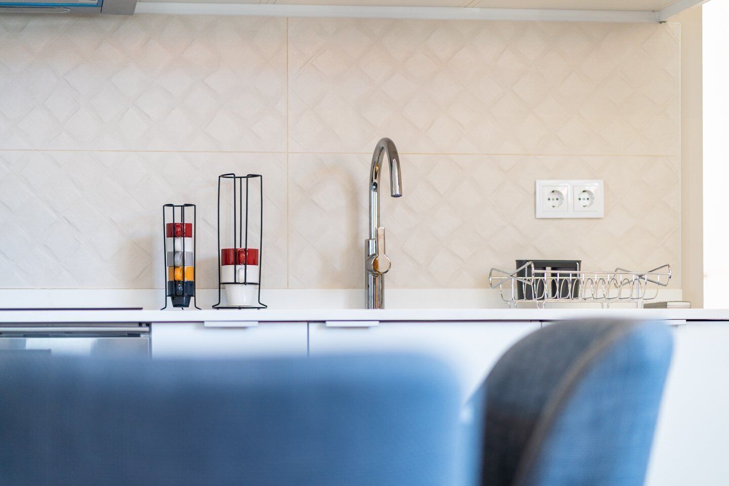A modern kitchen with a white countertop, a stainless steel faucet, and a wine rack.