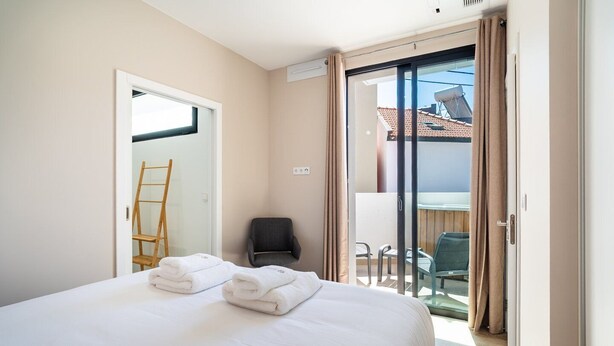 Una habitación de hotel con una cama, una silla, una escalera y un balcón con sillas.