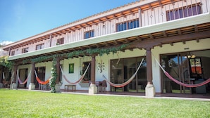 Um edifício de dois andares com varanda coberta, colunas e gramado.