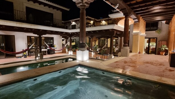 Un área de piscina con hidromasaje, hamacas y mobiliario de exterior.