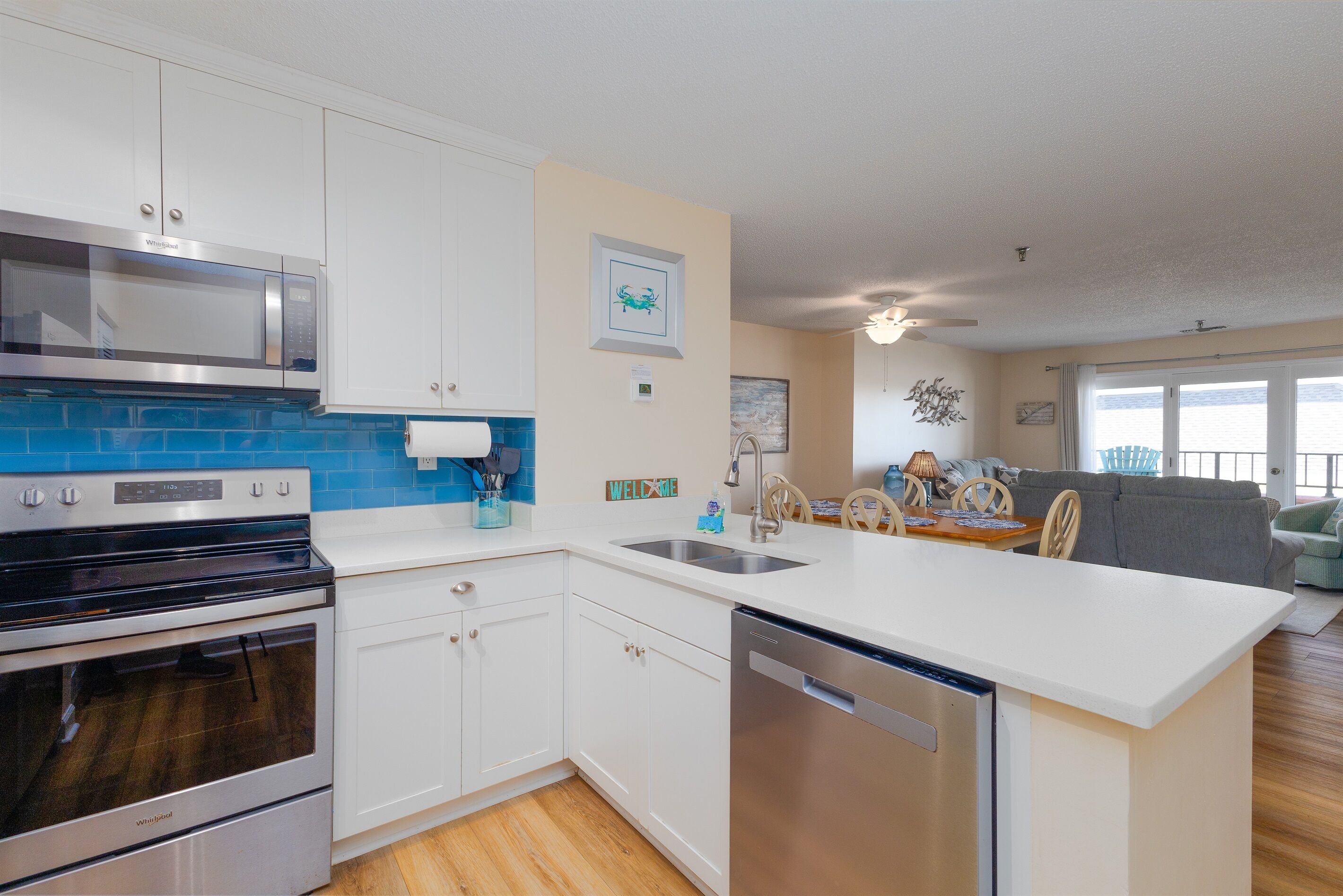 A modern kitchen with white cabinets, a stainless steel microwave, a built-in oven, and a dishwasher.