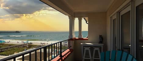Un balcone con vista sulla spiaggia e sull'oceano, un tavolino e una sedia.