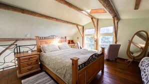 A bedroom with a wooden bed, bedside tables, a chair, a mirror, and a window.