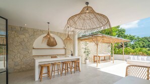 Una cucina moderna con parete in pietra, sgabelli da bar in legno e lampadario a sospensione.