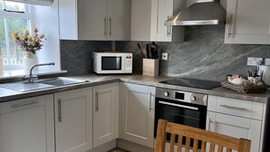 A modern kitchen with grey cabinets, a microwave, a stove, and a wooden dining table.