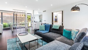 A modern living room with a grey sofa, a coffee table, and a dining area with chairs and a table. - Tufnell Park retreat close to Hampstead Heath (London)