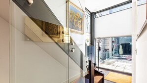 A modern staircase with glass railings, a wooden handrail, and a colorful rug at the bottom. - Tufnell Park retreat close to Hampstead Heath (London)
