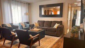 Un salon comprenant un canapé, des fauteuils, une table basse et un tapis.