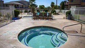 Une piscine de forme circulaire, entourée d’une terrasse en béton et d’une clôture blanche.