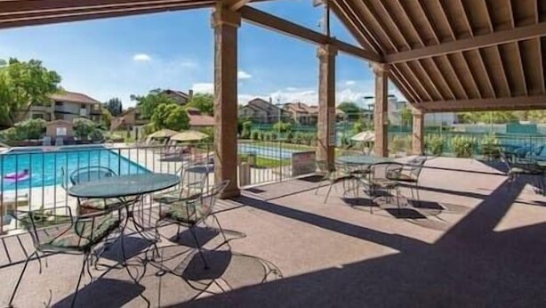 Un espace piscine extérieur doté d’un patio couvert, de chaises longues et offrant une vue sur le quartier environnant.