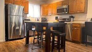 Une cuisine moderne avec des meubles en bois, des appareils en acier inoxydable et un îlot central doté de tabourets de bar.