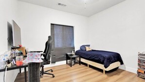 A bedroom with a bed, a desk with a computer, a chair, a window with blinds, and a bookshelf. - Beautiful Victorville Home with all the amenities (Victorville)
