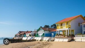A beachfront property with multiple colorful buildings, including a prominent yellow house with a red roof.