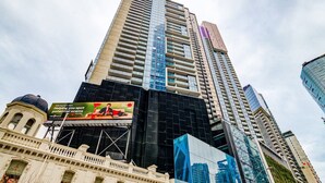 A high-rise building with a modern glass facade, a prominent billboard advertising a payment alert service, and a classical building with a dome at the base. - 3-bedroom apartment with Parking, Gym, Pool near Crown Casino & Eureka Tower (Southbank)