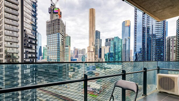A city view from a balcony with a glass railing, a table, and a chair. - 3-bedroom apartment with Parking, Gym, Pool near Crown Casino & Eureka Tower (Southbank)