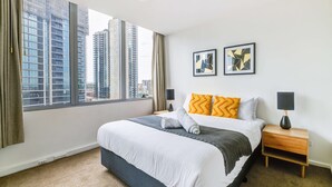 A modern hotel room with a large bed, two side tables, a window with curtains, and city views. - 3-bedroom apartment with Parking, Gym, Pool near Crown Casino & Eureka Tower (Southbank)