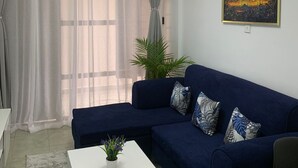 A living room with a dark blue sofa, white coffee table, and a painting on the wall.