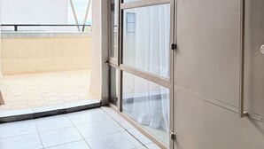 A hotel room with a sliding glass door leading to a balcony, a large wardrobe with the label "A1005", and a sign with the word "TSAVO".