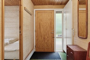 A bedroom with a wooden door, a bed, a dresser, and a mirror.