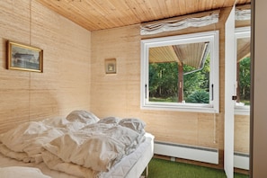 Une chambre à coucher avec un lit, une fenêtre et une porte donnant sur l’extérieur.