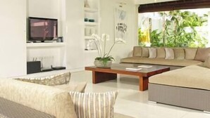A modern living room with a sofa, a coffee table, and a television. - Villa Asante | 4BR Family Villa Near Echo Beach | Pool, Chef (Canggu)