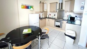 Een moderne keuken met een eettafel, stoelen, een koelkast, oven, magnetron en gasfornuis.