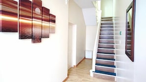 Een hal met houten vloer, een trap en kunstwerken aan de muur.
