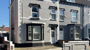 Een woonhuis met twee verdiepingen, een erker, een witte deur en een klein terras.