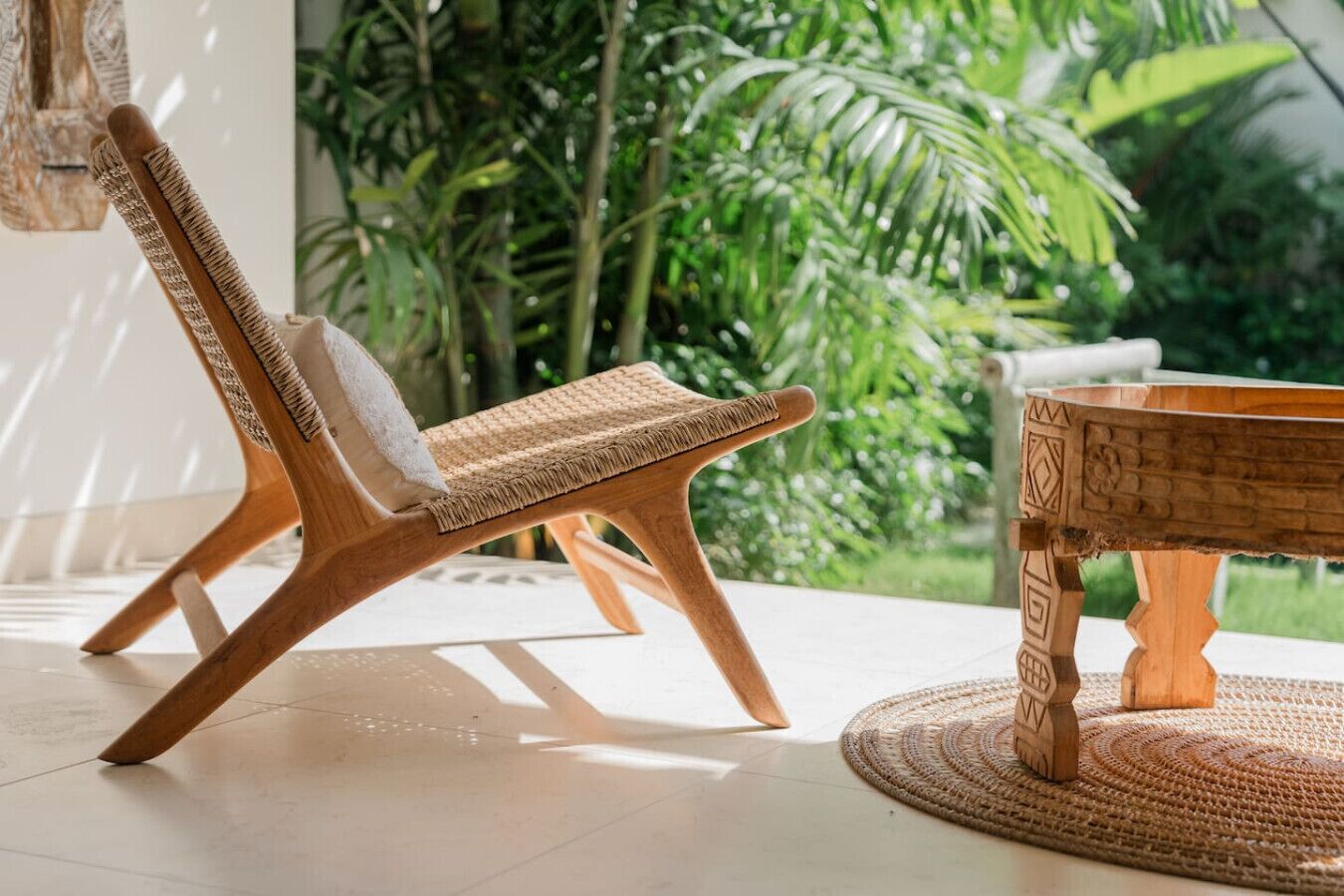 Une chaise en bois avec une assise et un dossier en osier tressé, une table en osier tressé ornée d’un motif géométrique, et un tapis de sol en osier tressé.