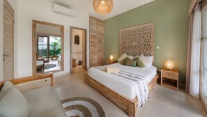 Ein Schlafzimmer mit einem großen Bett, einem Holzkopfteil, einem Spiegel, einem Nachttisch mit Lampe und Blick ins Freie.