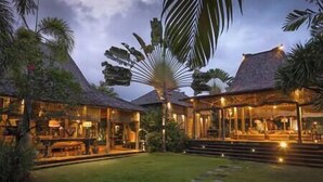A resort with multiple buildings, a well-maintained lawn, and a palm tree. - Villa Zelie by Elite Havens (Badung)
