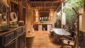 A rustic bathroom with a wooden floor, a large bathtub, and a wooden vanity with decorative items. - Villa Zelie by Elite Havens (Badung)