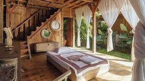 A wooden room with a bed, a staircase, and a view of greenery outside. - Villa Zelie by Elite Havens (Badung)