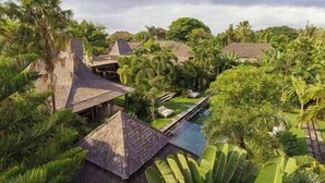 A resort with multiple thatched-roof structures, a swimming pool, and lush tropical vegetation. - Villa Zelie by Elite Havens (Badung)