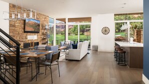 A spacious living area with a stone fireplace, a dining table, and a kitchen area with a bar.