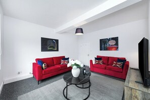 A modern living room with two red sofas, a black coffee table, and a television.