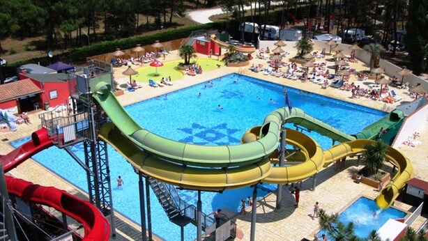 A water park with multiple slides, a central pool, and sun loungers.