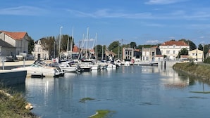 A marina with several boats docked, surrounded by buildings with red-tiled roofs.