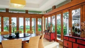 A spacious room with a large dining table, comfortable seating, and a red cabinet. - Villa Semarapura | 5BR Luxury Oceanfront Villa | Pool & Full Staff (Kabupaten Badung)