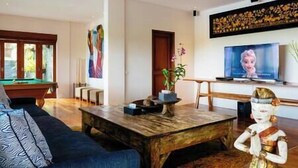 A modern living room with a pool table, a sofa, a coffee table, and a television. - Villa Semarapura | 5BR Luxury Oceanfront Villa | Pool & Full Staff (Kabupaten Badung)