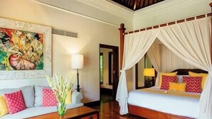 A bedroom with a four-poster bed, a sofa with patterned cushions, and a painting on the wall. - Villa Semarapura | 5BR Luxury Oceanfront Villa | Pool & Full Staff (Kabupaten Badung)