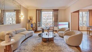 A modern living room with a large window, a round glass coffee table, and a beige sofa.