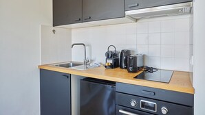 Een kleine keuken met een spoelbak, een koffiezetapparaat, een broodrooster en een vaatwasser.