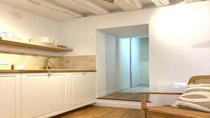 A modern kitchen with white cabinets, a wooden countertop, and a built-in sink. - Apartment Saint Germain des Pres Bon Marche (Paris)