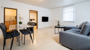 Una sala de estar moderna con una mesa de comedor, sofá y televisor.