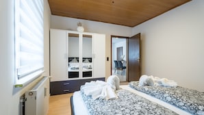 Ein Schlafzimmer mit zwei Betten, einem Kleiderschrank, einem Heizkörper und einem Spiegel.