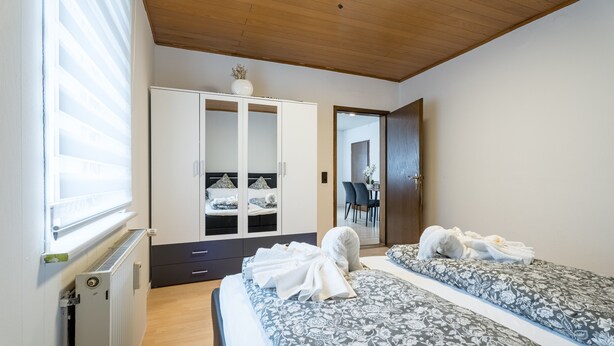 Un dormitorio con dos camas, un armario, un radiador y un espejo.