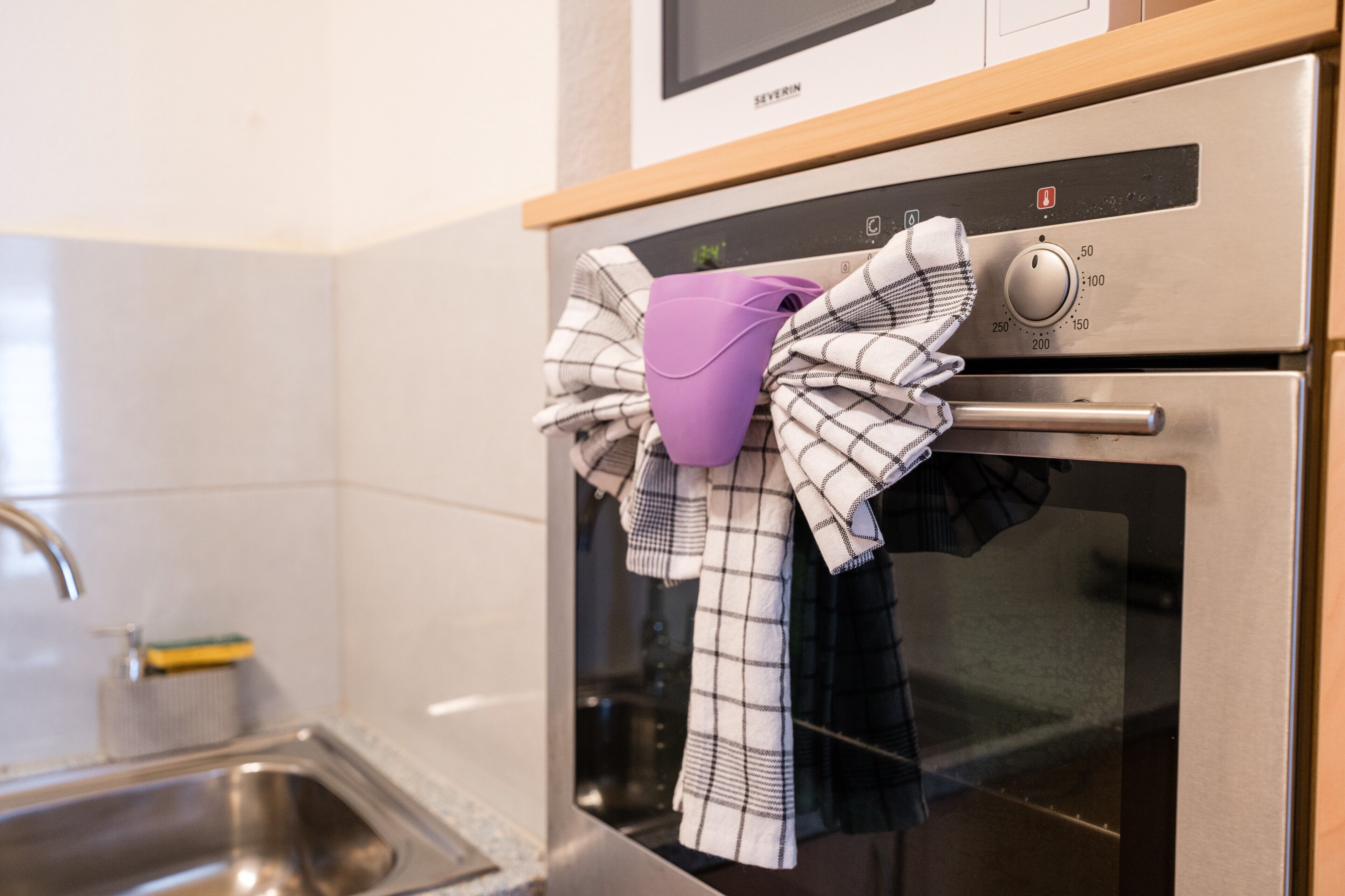 A kitchen with a stainless steel oven, a microwave above it, and a sink with a faucet.