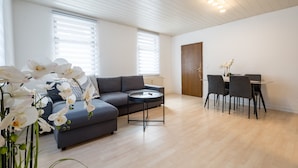 Ein modernes Wohnzimmer mit einer Couch, einem Esstisch mit Stühlen und einem kleinen runden Tisch.