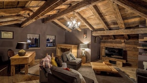 A rustic interior with exposed wooden beams, a fireplace, a sofa, a coffee table, and a television. - Chalet La Roche du Renard - 300 m² chalet in Gérardmer, sauna (Gérardmer)